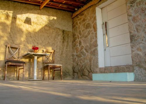 a table and two chairs next to a wall with a door at Paradise Camp in Monte das Gameleiras