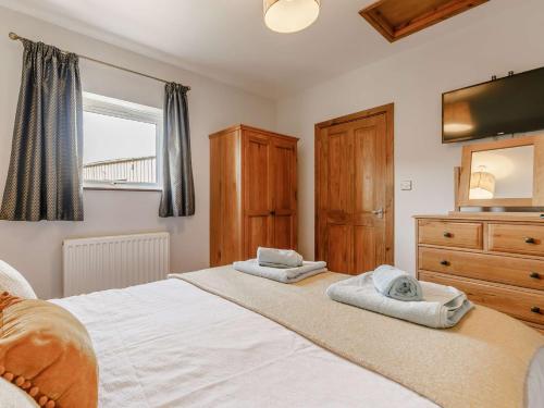 a bedroom with a bed and a dresser and a television at 1 Bed in Sennen CLOPC in St Just