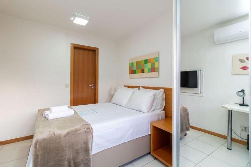 Un dormitorio con una cama blanca y un espejo. en Depto frente Lago Paranoá - CLR314, en Brasilia