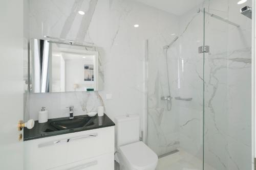 a white bathroom with a sink and a shower at A balcony over Funchal and sea Monte White House in Funchal