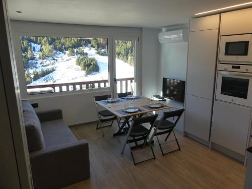 eine Küche und ein Esszimmer mit einem Tisch und einem Fenster in der Unterkunft Ideal per una escapada in Bordes d´Envalira 