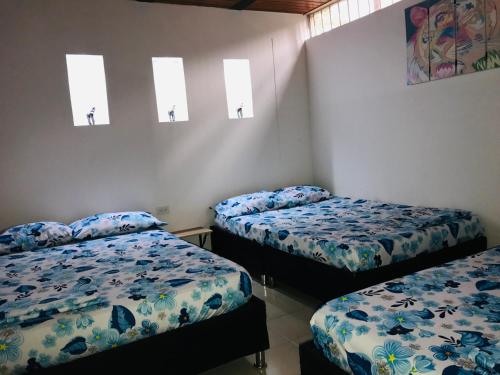 a room with two beds and two windows at EL DESCANSO DEL HACARITAMA in Melgar