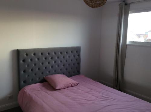Una cama con una almohada rosa encima. en Villa St. Georges en La Rochelle