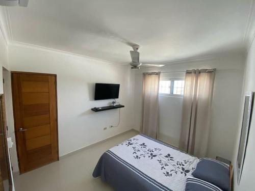 a bedroom with a bed and a tv and a door at Peaceful and Cozy Condo in Costa Verde in Santo Domingo