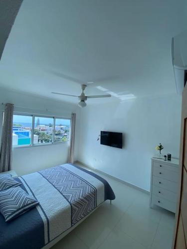a white bedroom with a bed and a ceiling fan at Peaceful and Cozy Condo in Costa Verde in Santo Domingo