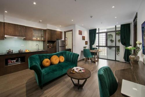 a living room with a green couch and a kitchen at The Bloom Hanoi - Bespoke Living in Hanoi