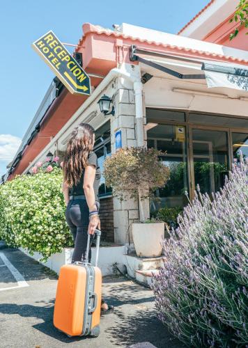a woman with a suitcase in front of a store at Hotel Duc de Vendôme in Vinaròs
