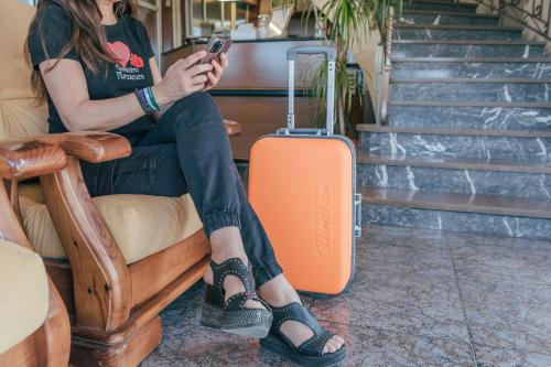 a woman sitting in a chair with a suitcase at Hotel Duc de Vendôme in Vinaròs