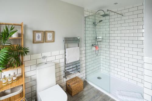 ein Badezimmer mit einer weiß gefliesten Dusche und einer Badewanne in der Unterkunft Contemporary 5 Bedroom with Garden North Finchley in London