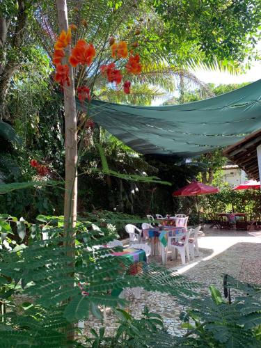 een patio met een tafel en stoelen en een boom bij Despertamar- Hospedagem em Calhetas in Cabo de Santo Agostinho