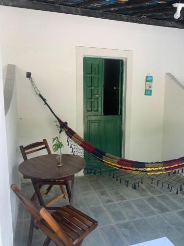 een hangmat in een kamer met een tafel en een groene deur bij Despertamar- Hospedagem em Calhetas in Cabo de Santo Agostinho