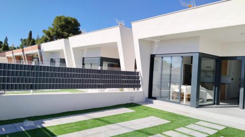 una casa blanca con césped delante en Maison neuve moderne en Los Baños