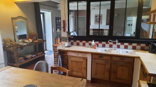 - une cuisine avec un évier, une table et un miroir dans l'établissement maison en campagne proche circuit des 24 h du Mans, à Allonnes