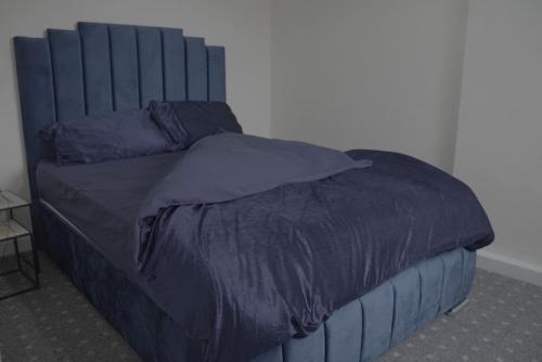 a bed with a blue comforter on top of it at Luxury 2 Bed Apartment London Twickenham in Hounslow