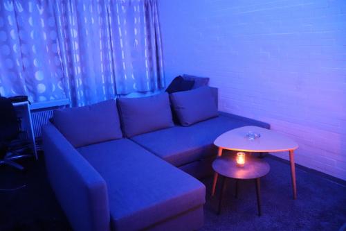 een woonkamer met een blauwe bank en een tafel bij Cozy one room apartment in Herlev