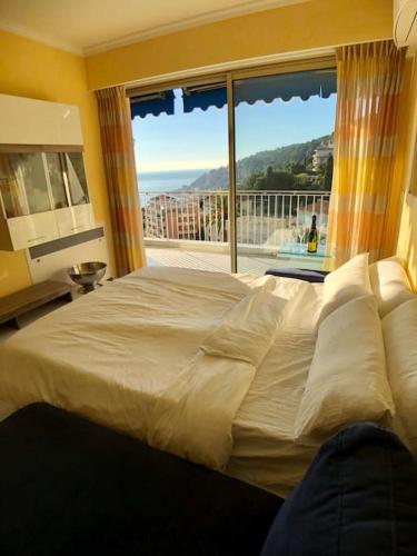 une chambre avec un grand lit et une grande fenêtre dans l'établissement Appartement „Bellevue“ Villefranche-sur-Mer, à Villefranche-sur-Mer