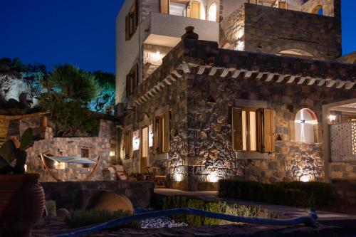 - un bâtiment en pierre avec des lumières allumées la nuit dans l'établissement Traditional House Meloi, à Patmos