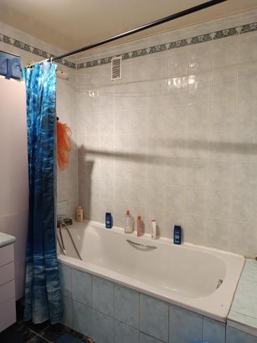 a bath tub with a blue shower curtain in a bathroom at Chambre lit double, proche de Orly, Gare TGV Massy, RER in Chilly-Mazarin
