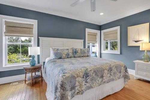 ein blaues Schlafzimmer mit einem Bett und zwei Fenstern in der Unterkunft Luxury Beach Front Home: Breath Taking Views in Tybee Island