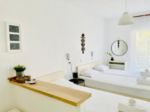 a white bedroom with two beds and a table at Thalassa Garden Studios in Pefkohori