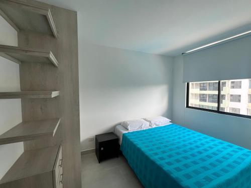 een slaapkamer met een blauw bed en een raam bij Hermoso Apartamento moderno y vacacional in Ricaurte