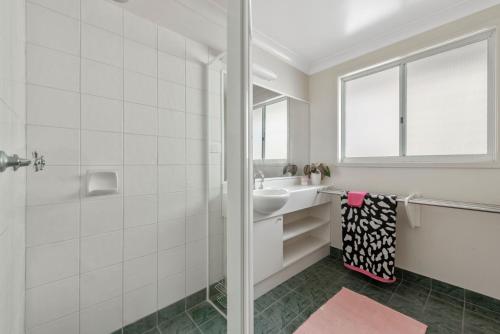 a white bathroom with a sink and a mirror at Sapphire Views - Narrawallee Beach in Narrawallee