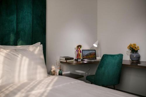a bedroom with a bed and a desk with a laptop at The Bloom Hanoi - Bespoke Living in Hanoi