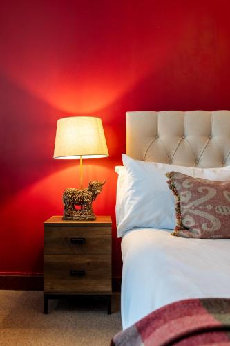 Una cama con mesita de noche con una lámpara. en The Bull on the Green, en Newick