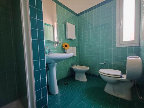W wyłożonej zielonymi kafelkami łazience znajduje się umywalka i toaleta. w obiekcie Casa Vacanze La Pineta del Mare w mieście Torre Ovo