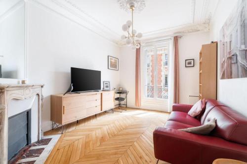 un salon avec un canapé rouge et une télévision dans l'établissement Appartement Familial Parisien, à Paris