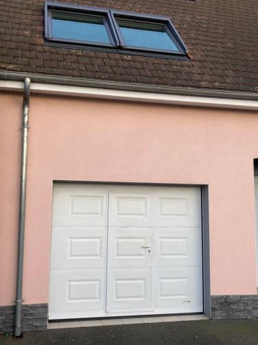 una porta bianca in un garage su una casa rosa di studio indépendant 800 m de la gare du Mans a Le Mans