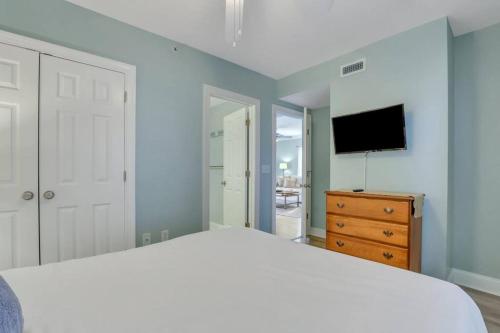 a bedroom with a white bed and a television at 2 Bed Condo Walk to the Beach in Tybee Island