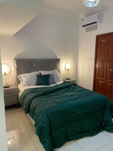 リーブルヴィルにあるSuperbe appartement meublé en résidence LBVのベッドルーム1室(緑色の大型ベッド1台、ランプ2つ付)