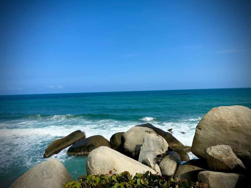 a group of rocks on the beach with the ocean at Eco Hotel Amanecer Tayrona in El Zaino