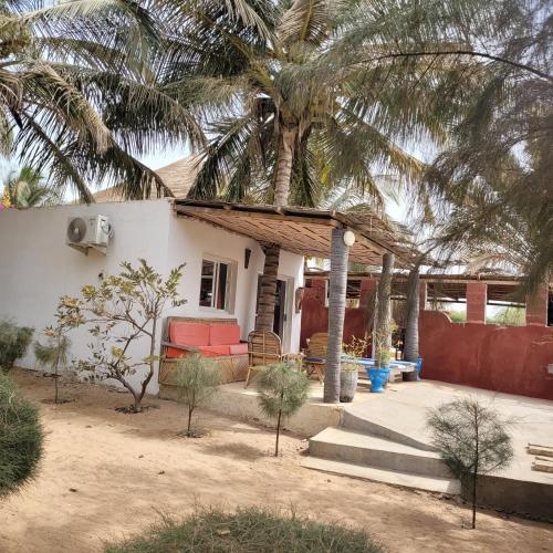 a small house with a palm tree in front of it at la villa sur la plage in Palmarin