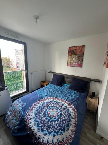 a bedroom with a bed with a blue comforter and a window at Chambre double proche Arena La Defense in Nanterre