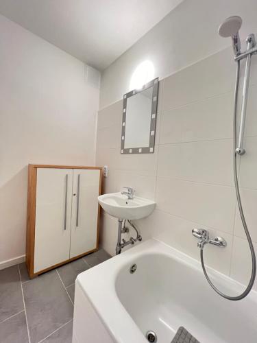 een witte badkamer met een wastafel en een bad bij Wohnung in Schlachthausgasse in Wenen