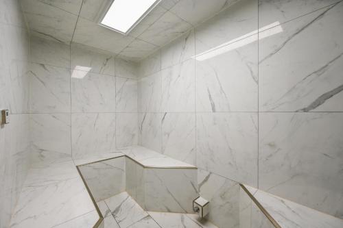 La salle de bains est pourvue de murs en marbre blanc et d'une lucarne. dans l'établissement Pelican Beach Resort by Panhandle Getaways, à Destin