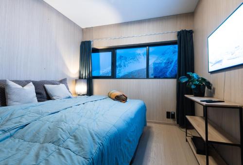 a bedroom with a blue bed and two windows at New luxury cabin near Henningsvær Lofoten in Kleppstad