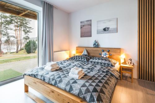 een slaapkamer met een bed en een groot raam bij Apartmány Dolce Vita Lipno 511-5 s výhledem na jezero in Lipno nad Vltavou