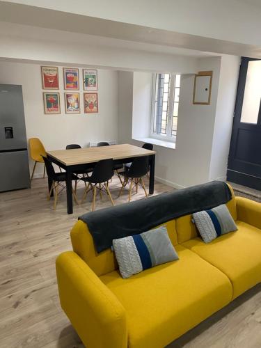 een gele bank in een woonkamer met een tafel bij La Maison du Roi Arthur in Carcassonne