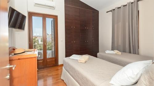 a bedroom with two beds and a tv and a window at Villa Sobre - Spacious And Comfortable in Kounoupidhianá