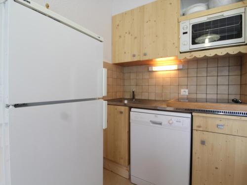 La cuisine est équipée d'un réfrigérateur blanc et d'un four micro-ondes. dans l'établissement Studio 5 pers accès direct pistes avec wifi et lave-vaisselle Termignon - FR-1-508-250, à Termignon