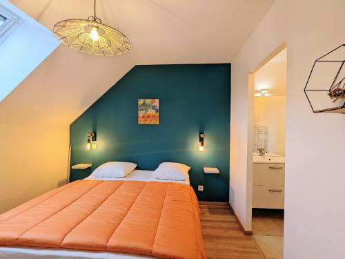 - une chambre avec un lit orange et un mur bleu dans l'établissement Gîte de charme avec jacuzzi privé près des Châteaux de la Loire et du Zoo de Beauval - FR-1-591-565, à Villentrois