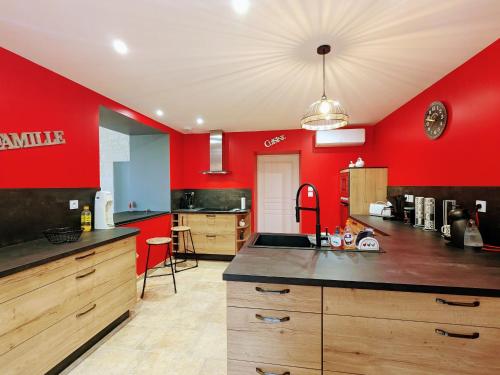 une grande cuisine avec des murs rouges et un comptoir dans l'établissement Gîte de charme avec jacuzzi privé près des Châteaux de la Loire et du Zoo de Beauval - FR-1-591-565, à Villentrois
