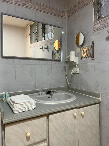 La salle de bains est pourvue d'un lavabo et d'un miroir. dans l'établissement Hotel Armenia Centro, à Armenia