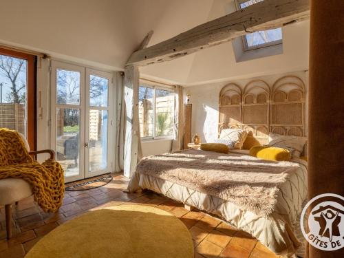 a bedroom with a bed and a chair and windows at Charmante maison en Anjou Bleu, 2 pers, terrasse, poêle à bois, équipements bébé, cuisine équipée - FR-1-622-72 in Noëllet