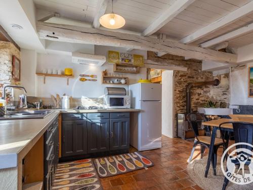 une cuisine avec un réfrigérateur blanc et une table dans l'établissement Charmante maison en Anjou Bleu, 2 pers, terrasse, poêle à bois, équipements bébé, cuisine équipée - FR-1-622-72, à Noëllet