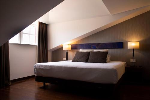 a bedroom with a large bed with two lamps at Hotel Carris Porto Ribeira in Porto