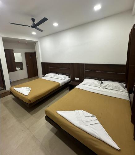 a room with two beds and a ceiling at Shreetej Executive in Kolhapur